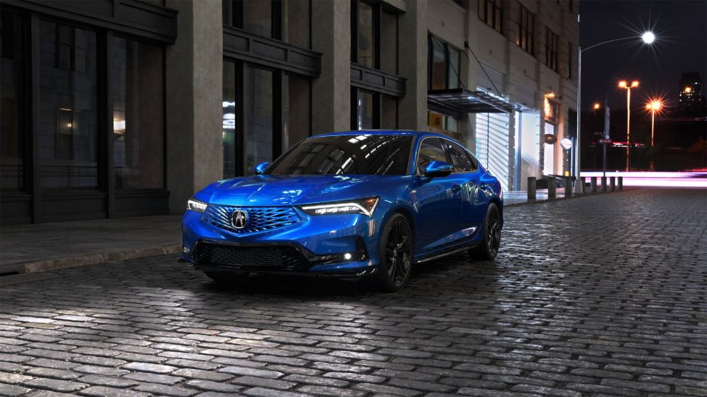 A blue sedan parked on a cobblestone street at night, likely the 2026 Genesis G70.