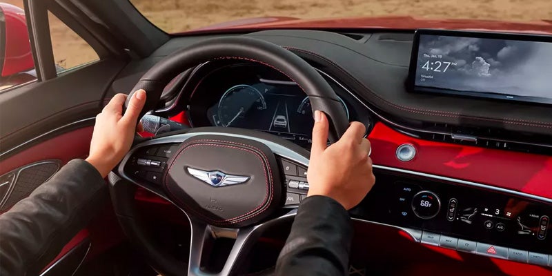 Genesis GV70 interior featuring a digital display, steering wheel, and red dashboard accents.