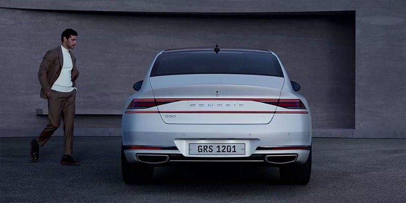 Person Moving Towards A Genesis G90 Vehicle Parked In Front Of A Wall